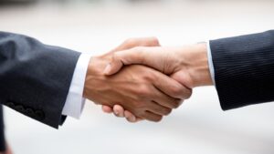 Two people in business suits shake hands.