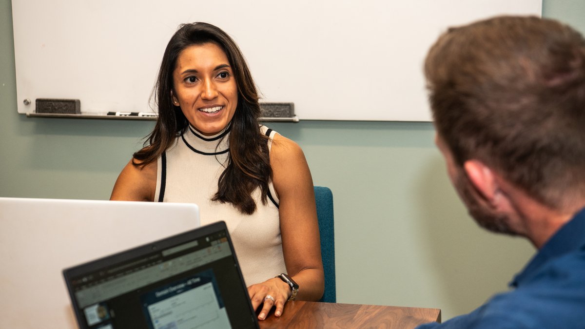 Two WSI Smart Marketing team members talking across a conference table with laptops open
